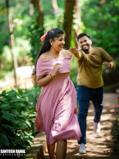 A fun and candid action shot of a couple playfully chasing each other on a garden path.
