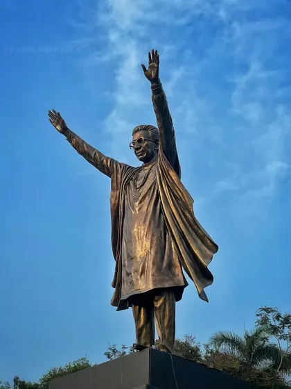 A powerful low-angle shot of the Balasaheb Thackeray statue in Mumbai, capturing the leader's commanding presence against a clear blue sky.
