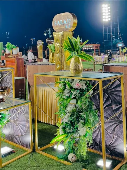 A modern salad bar setup with geometric gold stands and floral decor.