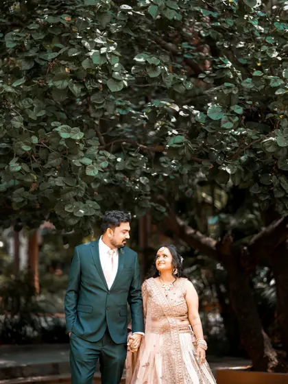 A classic walking shot of the couple, hand in hand, at their garden reception.