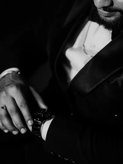 A stylish black and white shot of the groom adjusting his watch. This detailed portrait captures a sense of classic elegance and anticipation before the main event.