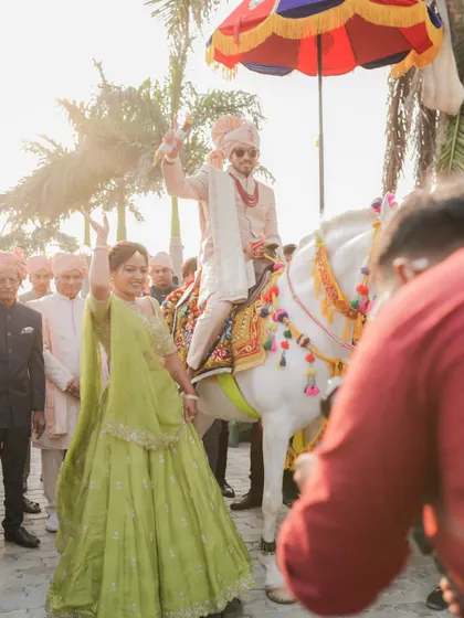 A bridesmaid, the sister of the groom, dancing in the baraat in a vibrant lime green lehenga, a perfect look for a daytime wedding.