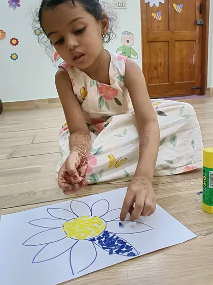 Sitting on the floor, this little Aster works on her paper flower art. We provide a comfortable and flexible environment for our creative sessions.