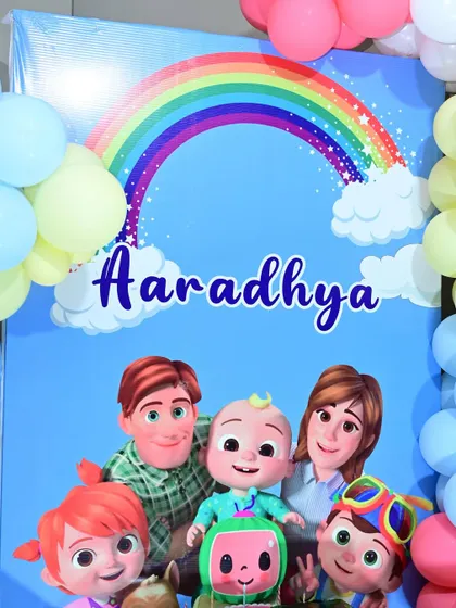 A close-up of the Cocomelon backdrop, featuring the whole family under a rainbow.