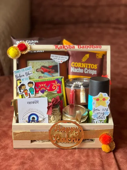 This sibling gift pack for Rakhi includes a mix of snacks, a tumbler, and a personalized photo frame.