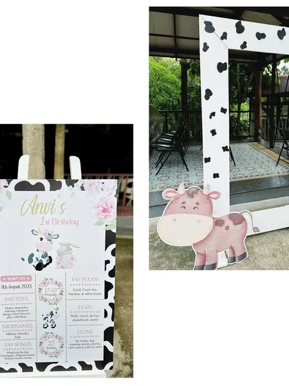 A personalized milestone board for Anvi's first birthday, paired with a cow-print photo frame, making for a great entrance detail.