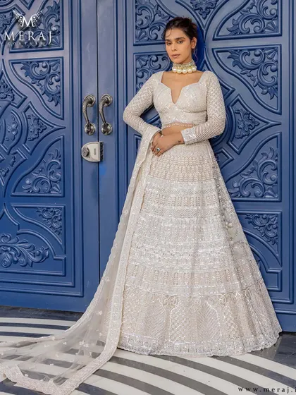 A silhouette that speaks volumes. This ivory lehenga from the 'Ruvaah' collection blends sharp structure with delicate craftsmanship, featuring fine mirror work and linear embroidery.
