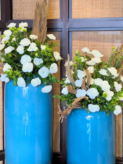 A pop of color with these bright blue vases filled with white ranunculus and dried wheat stalks, a perfect blend of modern and rustic.
