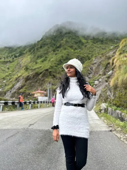 A stylish winter look on the roads of Sikkim. This photo shows how I incorporate fashion into my travels, modeling a chic belted sweater and hat against a mountain backdrop.