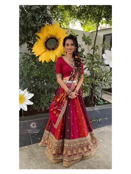 A full length shot of Prathima at her haldi ceremony. The makeup is bright and festive, with a pop of color on the lips that ties in with her multi colored lehenga.