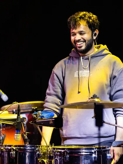 A lighter moment on stage, smiling as I play. My percussion setup is extensive, featuring cymbals, wood blocks, and various drums to create a rich soundscape.