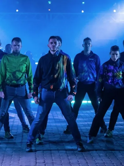 The full dance crew of "To Da Bone" strikes a powerful pose. The image captures the unity and collective energy of the group.