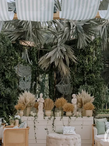 We created this lounge area by hanging crystal chandeliers from the trees, blending glamour with nature. The backdrop features dried pampas grass and classical statues for a touch of timeless romance.