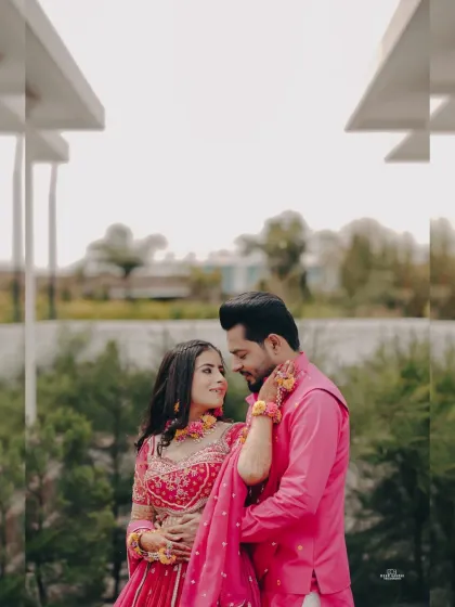 A beautiful portrait of the couple in their matching pink Haldi outfits. The floral jewelry and the outdoor setting add a fresh, romantic feel.