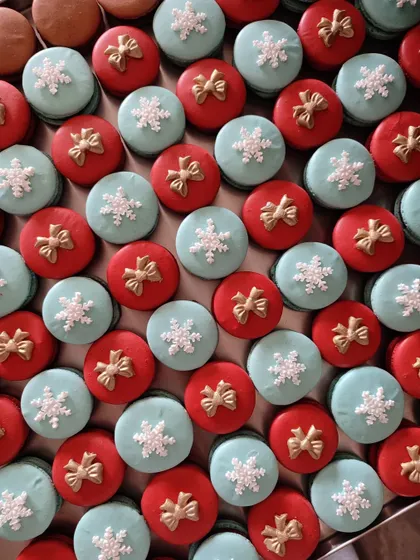 My Christmas macarons are a festive delight. This batch features red and light blue shells, decorated with tiny sugar bows and snowflakes, filled with a delicious ganache.