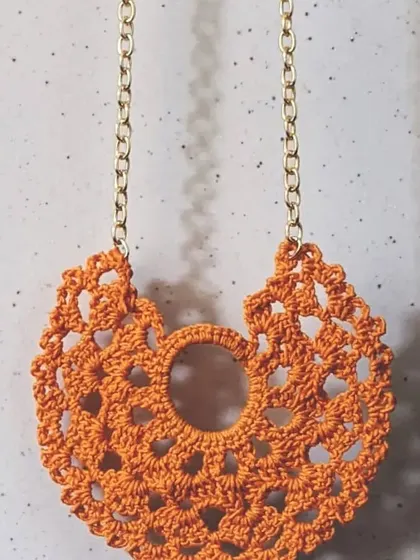 This vibrant orange lace pendant is perfect for adding a warm, artsy touch to your look. The intricate crochet pattern is lightweight and eye-catching.