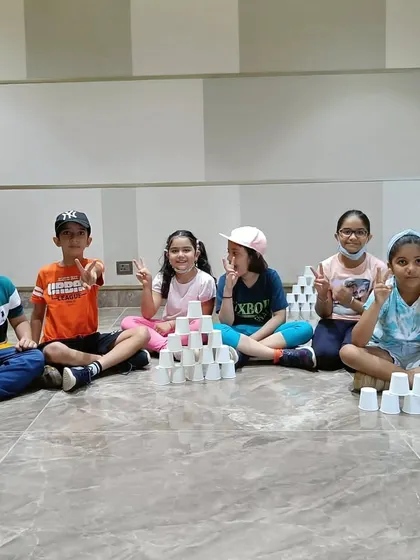 We blend fun and fitness to build strong and confident kids. Here, a group of children enjoys a cup stacking game, a fun activity that develops focus and coordination.