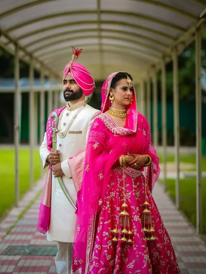 A regal portrait of a Sikh couple on their wedding day, showcasing their magnificent traditional outfits.
