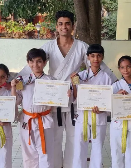 A Sensei stands with the medal winners from Purva Belmont dojo. This is a proud moment for both the students and their instructor.