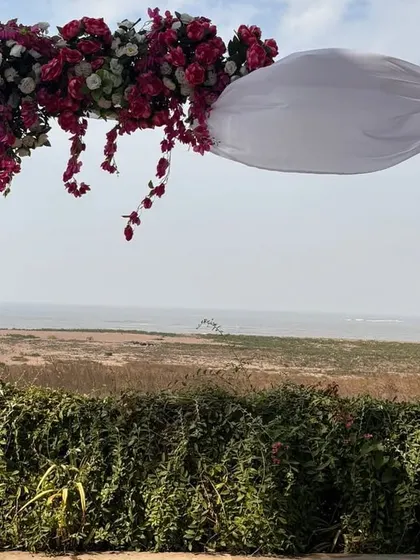 A simple yet stunning floral arch for a beachside wedding ceremony. The design frames the natural ocean view perfectly, creating a beautiful and serene setting for an intimate exchange of vows.