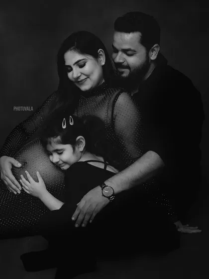 A sister's love for her new sibling. This black and white maternity photo beautifully captures the anticipation and excitement of a growing family.