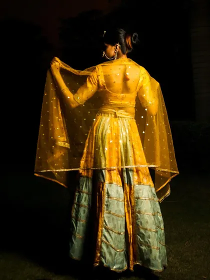 A view of the back of the lehenga, showcasing the sheer, sparkling dupatta and the design of the blouse back.