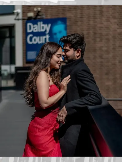An intimate and romantic moment on a city balcony. The close embrace and soft expressions create a feeling of a private world amidst the bustling city of London.
