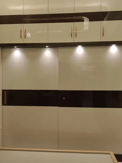 A modern bedroom deserves a modern finish. We gave this wardrobe a sleek, high-gloss Duco finish, combining classic white with a dark wood-tone band. The reflective surface adds a touch of luxury and makes the room feel brighter and more spacious.