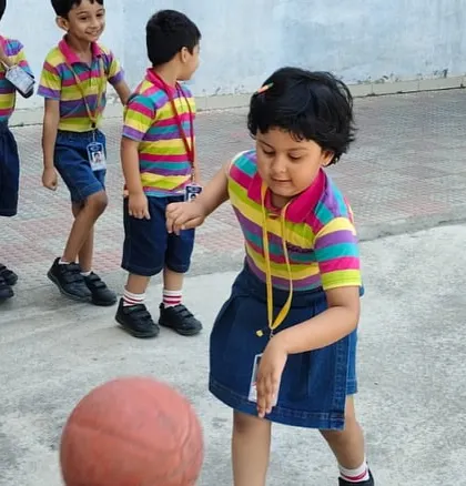 A young student focuses intently on dribbling the basketball, developing her motor skills and having fun at the same time.