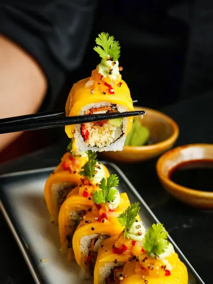 A close-up, moody shot of a mango sushi roll against a dark background. This style creates a sense of drama and sophistication, perfect for highlighting a chef's signature dish on a fine-dining menu.