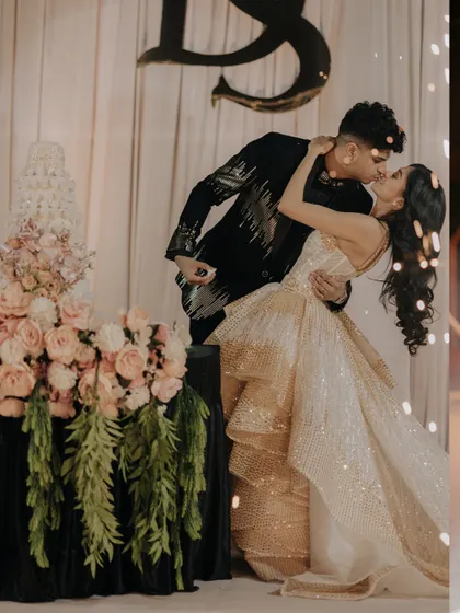 A romantic kiss by the wedding cake, with sparklers adding a magical touch to the background.