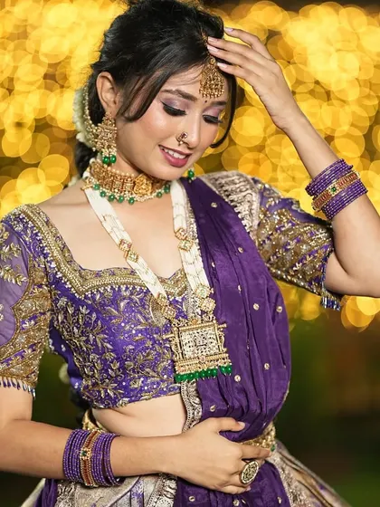 A beautiful shot showcasing the intricate handwork on this purple and silver semi-bridal lehenga. The blouse features detailed embroidery, and the entire outfit is designed to make you shine, especially with the beautiful bokeh lights in the background.