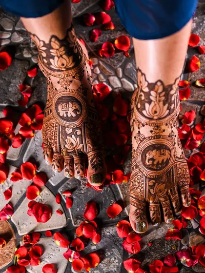 Another angle of the lotus and elephant themed foot mehendi, surrounded by rose petals.