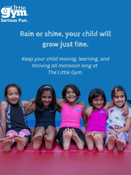 A group of smiling girls sit together with their arms around each other. A perfect image to convey that rain or shine, your child will grow just fine at The Little Gym.