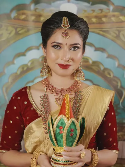 This is the quintessential South Indian Muhurtham look, radiating elegance and tradition. I focused on creating a flawless base, classic winged eyeliner, and a timeless red lip to complement the beautiful gold and red tones of the bride's attire.