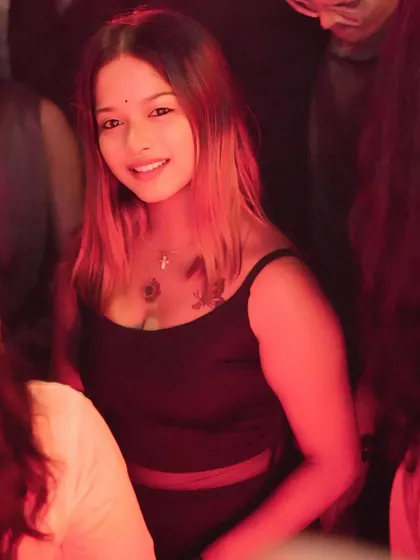 A close-up of a guest in the crowd, lit by the warm red lights of the club.