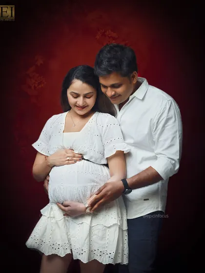 A beautiful moment of connection. The couple looks down at the baby bump together, sharing a private, happy thought.