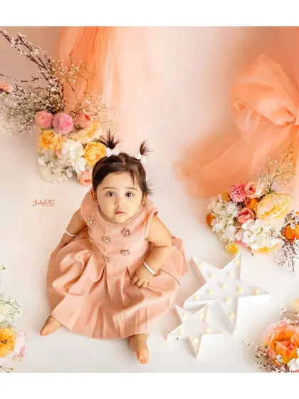 This little darling looks so sweet in her peach dress, surrounded by matching flowers. This theme is perfect for a soft and elegant milestone session.