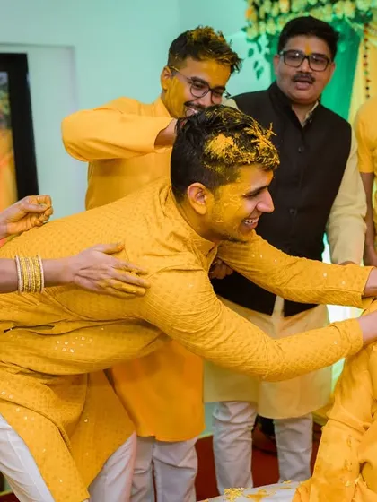 More friends join in on the fun, ensuring the groom is thoroughly covered in turmeric. These are the moments of pure, unscripted fun.