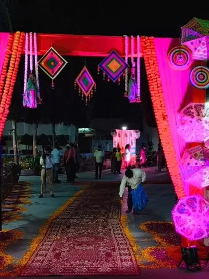 This is the same Mehendi entrance at night, showing how I use lighting to transform the space. The pink uplighting makes the colorful umbrellas and decorative hangings pop, creating a magical evening look.