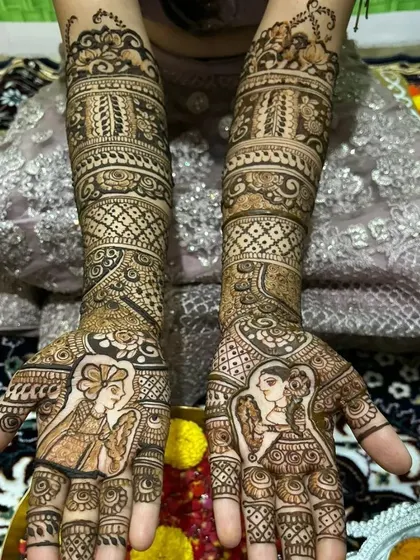 A full view of the intricate bridal-style mehndi with couple portraits. The design extends up to the elbows, featuring palanquin (doli) motifs and detailed geometric patterns.