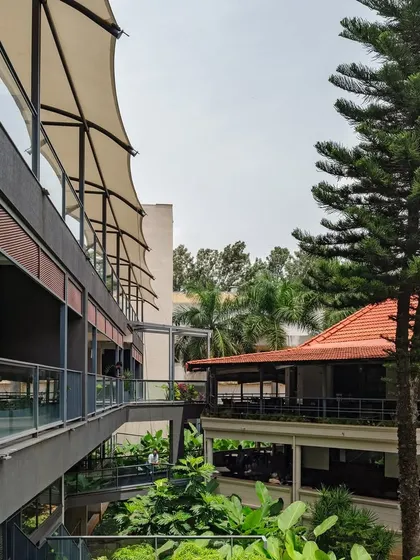 The new annexe building sits alongside the existing structures of the Koramangala Club. The design uses tensile fabric canopies and open terraces to create shaded, semi-outdoor spaces for recreation and socializing.