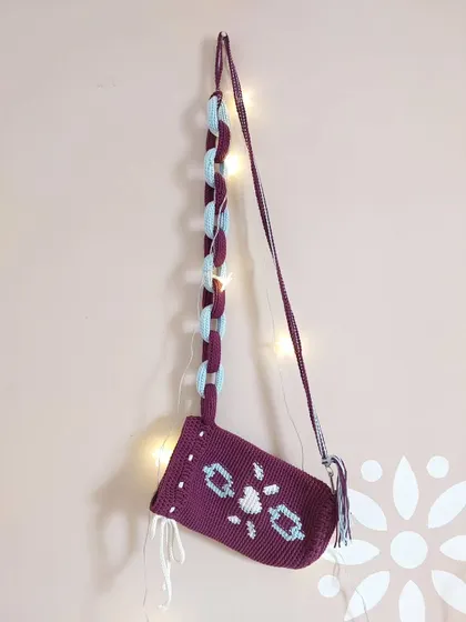 The Elara Bag hanging, showcasing its unique design with a tapestry crochet body and a chunky, two-toned chain strap.