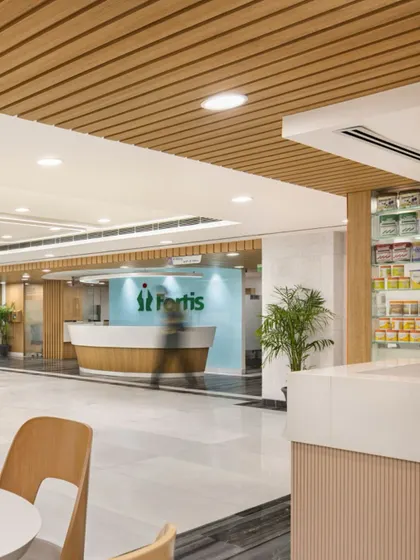 The reception area at Fortis Healthcare in Ludhiana combines warm wood tones with a clean, modern aesthetic. This space was part of an adaptive reuse project, transforming an existing structure into a high-performing, patient-friendly hospital.