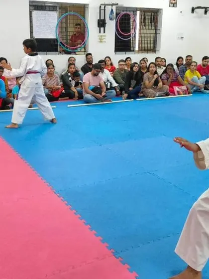 An instructor watches two young students practice their form.