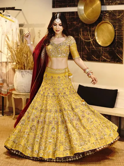 A beautiful shot of a bride or bridesmaid in a vibrant yellow lehenga. The twirling pose shows the full, magnificent flare of the heavily embroidered skirt.