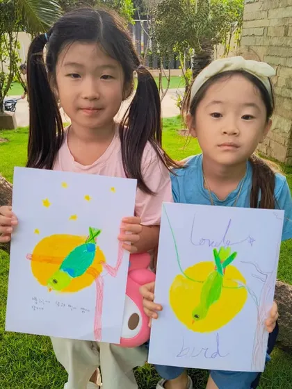 Two students from our parrot class holding up their colorful creations, each with its own unique charm.