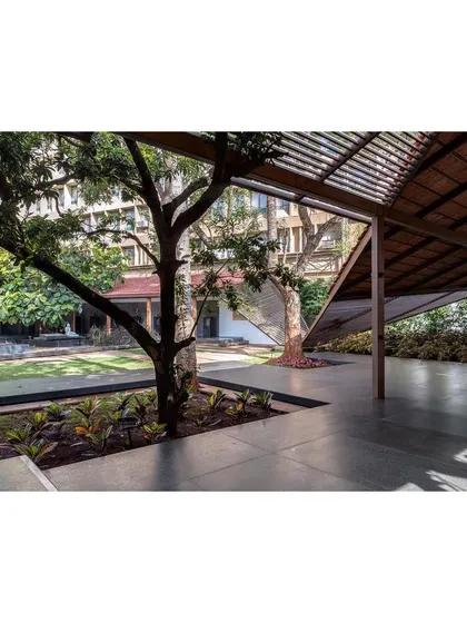 Existing trees were carefully preserved and integrated into the new design, acting as natural anchors within the open-air pavilions and courtyards.