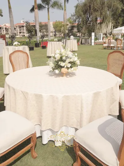 A wide view of the guest seating on the lush green lawn, creating a beautiful contrast with the white and gold decor.