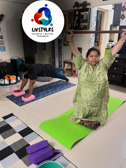Two clients work on different exercises, one holding a plank and the other practicing a seated stretch with a staff.